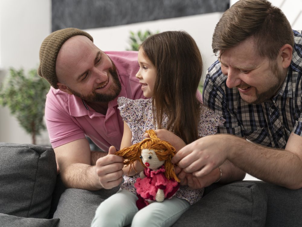 Two dads playing with their daughter